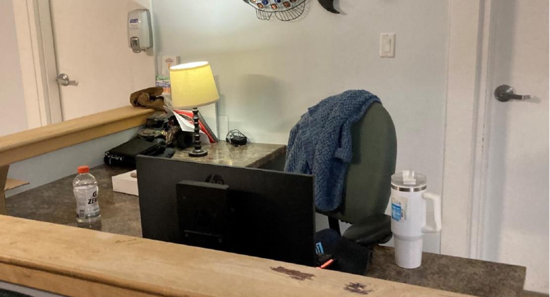 Office area with computer monitor, desk, desk lamp and two white doors in the background 