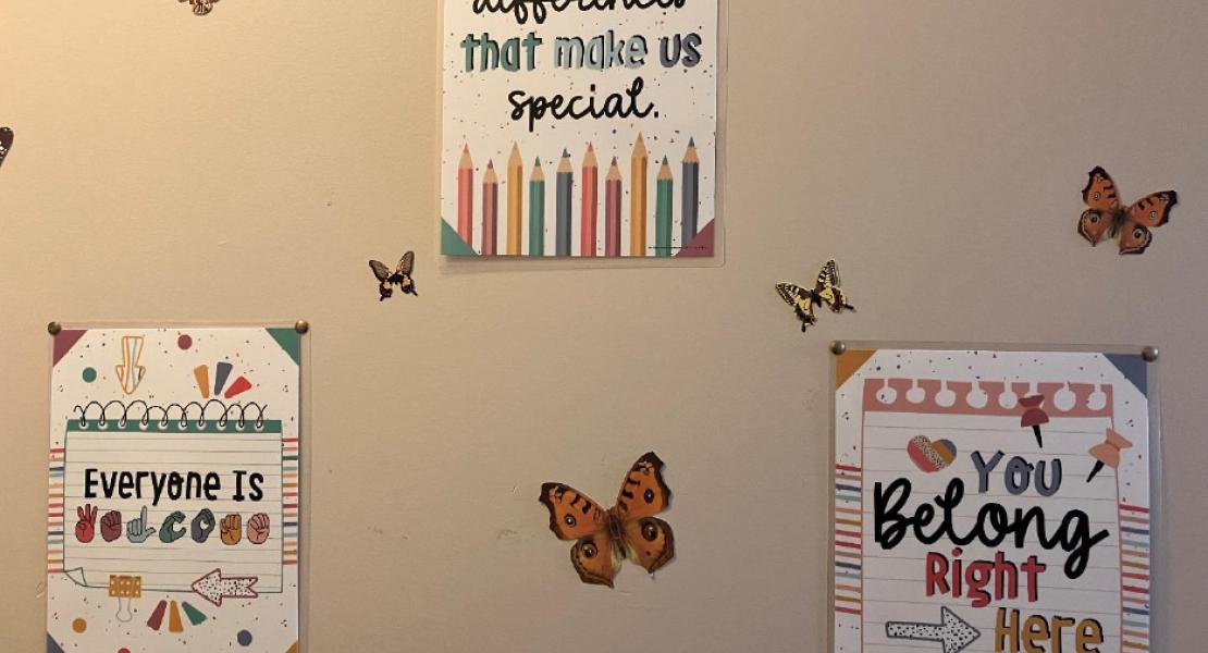 A beige wall with three colorful, motivational posters and butterfly decals