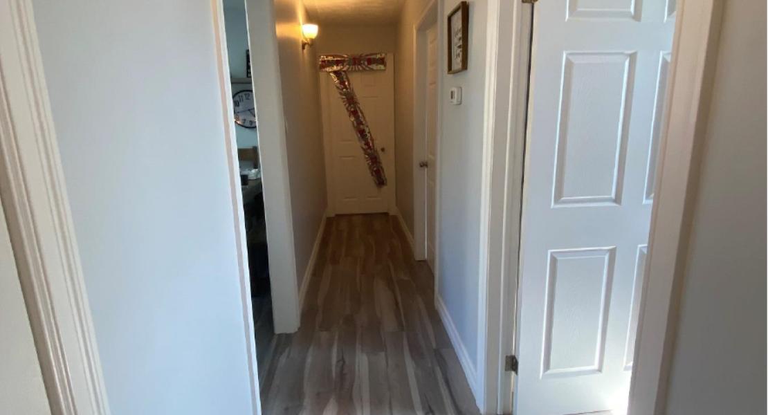 Hallway with wood floors, wall lights and three white doors 
