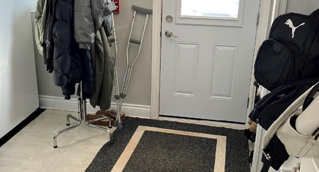An entryway with a rug, shoe rack and coat rack.  