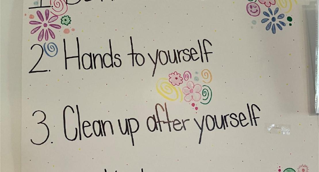 A paper poster with written “House Rules” displayed along with colourful flowers and patterns 