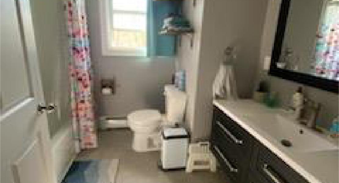 Bathroom with a mirror above a vanity with a sink, toilet and bathtub/shower. 