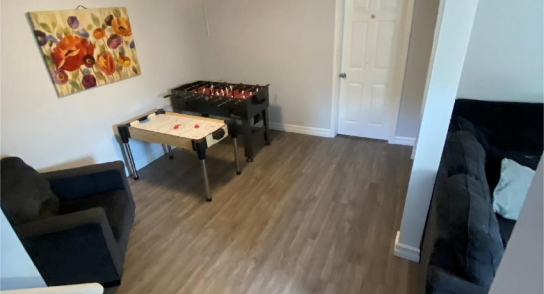 Recreation room with air hockey and fooseball tables, a chair and couch 