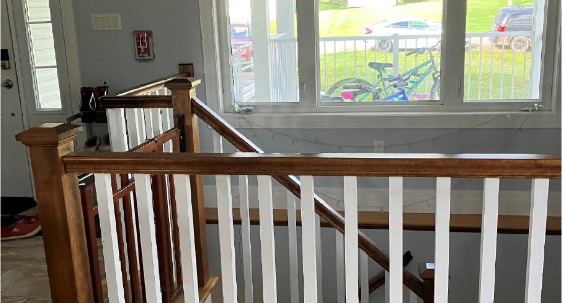  Stairwell by the front entrance with wooden and white railings, large window with pendant lights hanging from the ceiling 