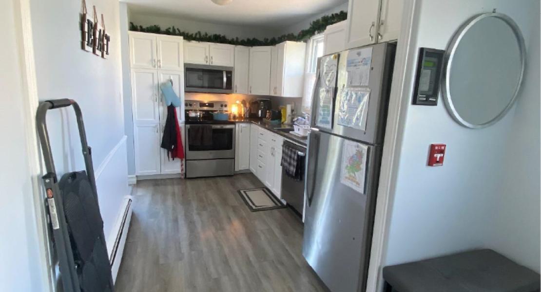  Kitchen with wood floors, a fridge, stove, microwave and white walls 