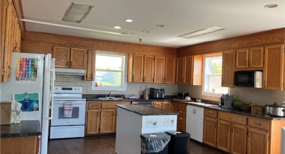 Large kitchen with wood cabinetry, island, stove, dishwasher, and white fridge 