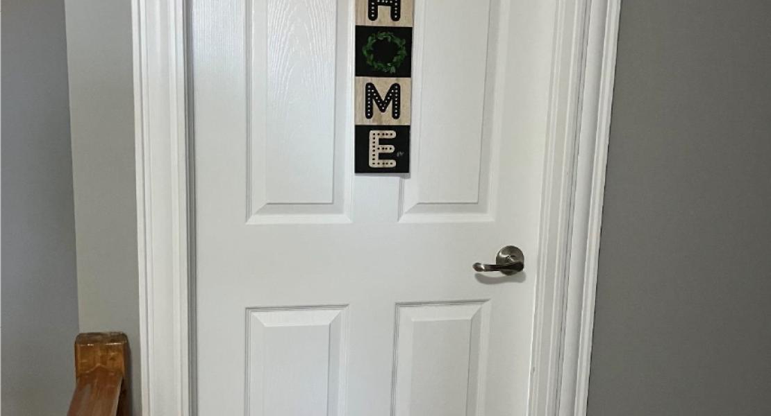  A white bedroom door with a sign that says “HOME” 