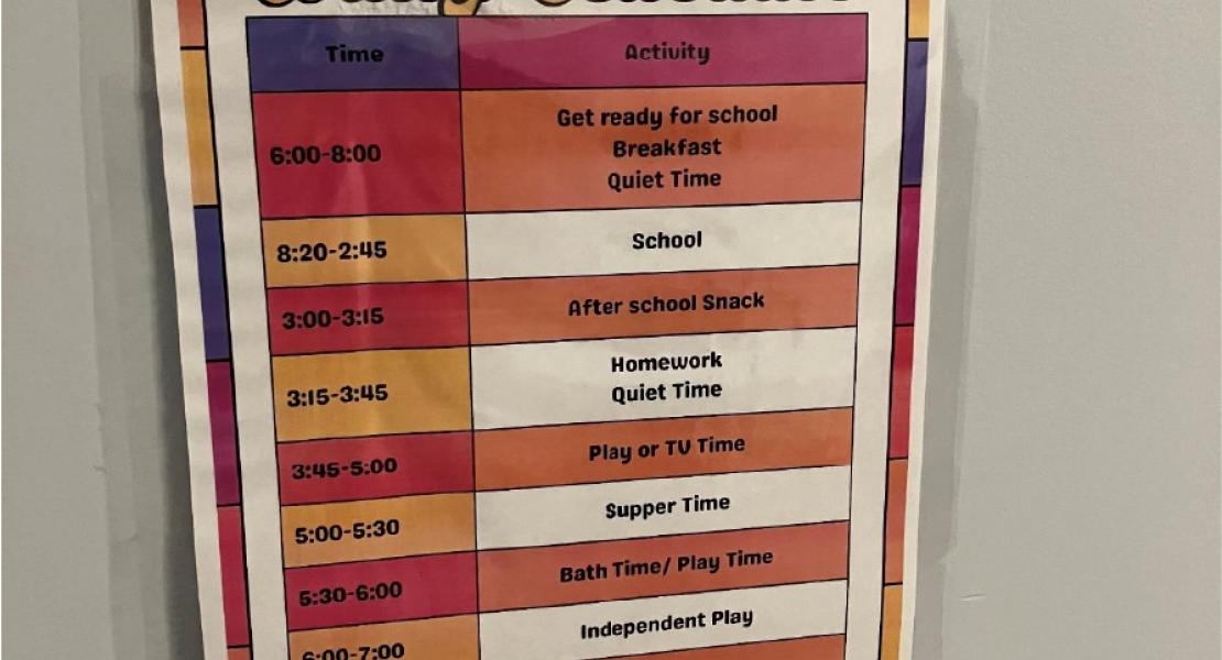 Colourful daily schedule poster listing times and activities, including school, meals, playtime, homework and quiet time. 