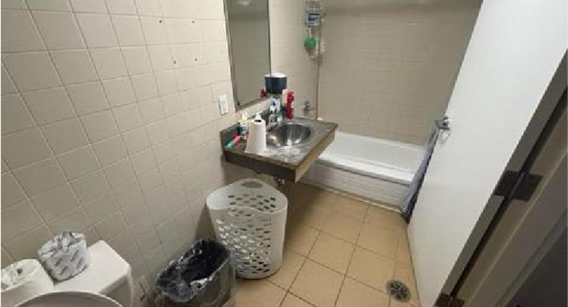 Bathroom with tile floor, bathtub, sink with mirror and laundry basket 