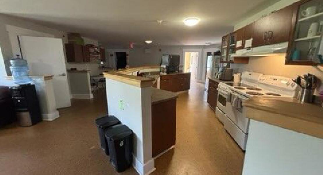 Kitchen with two stoves, countertop, cabinets, and brown flooring 